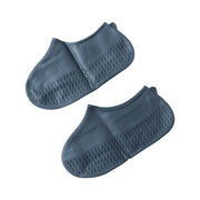 A pair of navy blue silicone shoe covers are displayed flat, showing their textured soles and smooth tops.