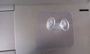 Minimalist transparent self-adhesive wall hook installed on a white wall.